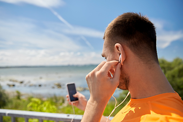 Image showing young man with smartphone and earphones outdoors