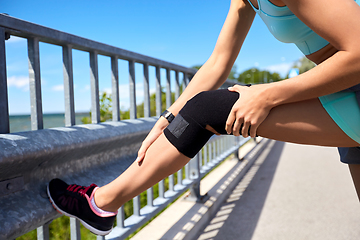 Image showing young woman in knee band doing sports outdoors