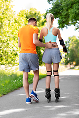 Image showing happy couple with roller skates riding outdoors