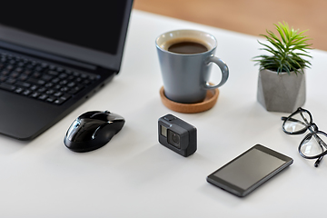 Image showing action camera and other media on office table