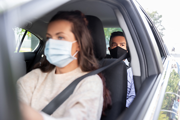 Image showing female driver in mask driving car with passenger