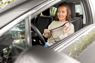 Image showing woman or female driver fastening seat belt in car