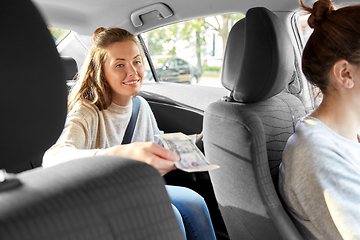 Image showing female passenger passing money to car driver