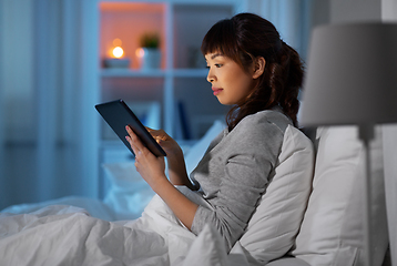 Image showing asian woman with tablet pc in bed at home at night