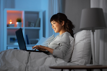 Image showing woman with laptop in bed at home at night