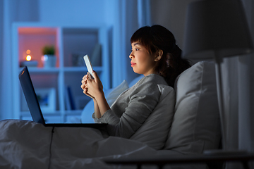 Image showing asian woman with smartphone in bed at night