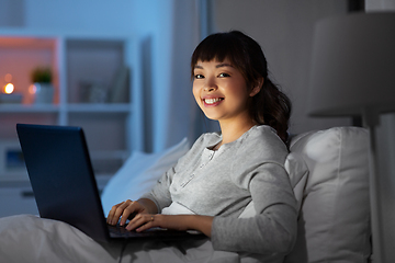 Image showing woman with laptop in bed at home at night