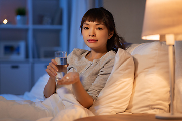 Image showing stressed asian woman taking medicine at night