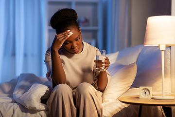 Image showing stressed african woman lying in bed at night