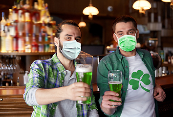 Image showing male friends in masks drinking green beer at bar