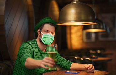 Image showing young man in mask drinking green beer at bar