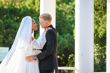 Image showing Mixed-racial newlyweds on a walk hugging and lovingly look at each other