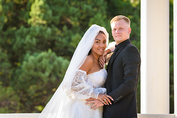 Image showing Mixed race newlyweds on a walk hugging and looking into the frame