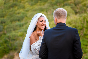 Image showing Black bride talking on the phone and looking happily at her white husband