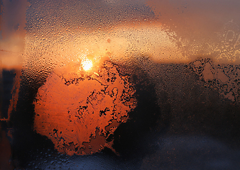 Image showing Ice patterns, water drops and sunlight on a winter window glasss