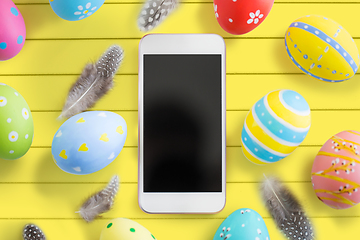 Image showing smartphone with easter eggs and feathers on table