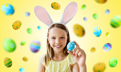 Image showing happy girl with colored easter egg on yellow