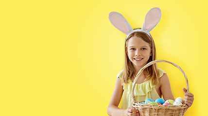 Image showing happy girl with colored easter eggs over yellow