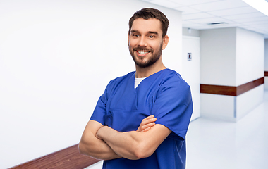 Image showing happy smiling doctor or male nurse in blue uniform