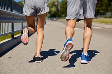 Image showing feet of sporty couple running along city road