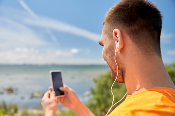 Image showing young man with smartphone and earphones outdoors