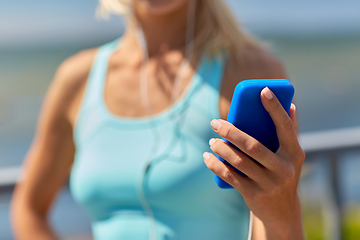 Image showing sporty young woman with smartphone and earphones