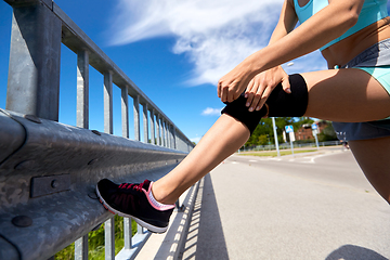 Image showing young woman in knee band doing sports outdoors