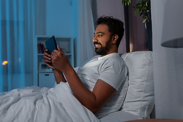 Image showing indian man with tablet pc in bed at home at night