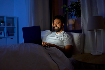 Image showing indian man with laptop in bed at home at night