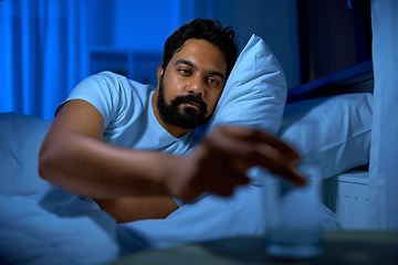 Image showing indian man drinking water in bed at night