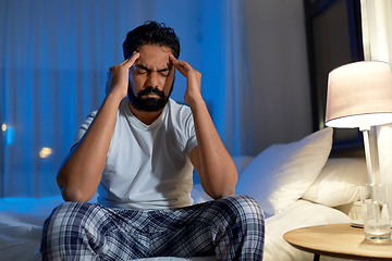 Image showing stressed indian man sitting on bed at night