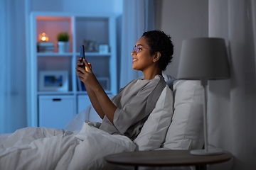 Image showing african woman with smartphone in bed at night