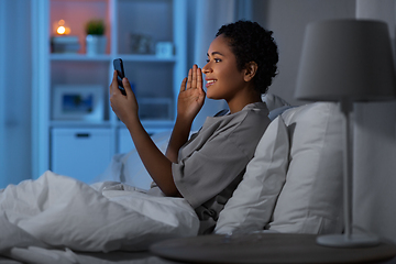 Image showing woman with phone having video call in bed at night