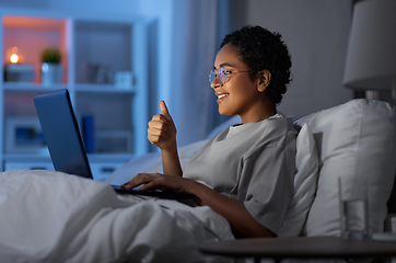 Image showing woman having video call on laptop in bed at night