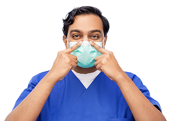 Image showing indian male doctor in blue uniform putting mask on