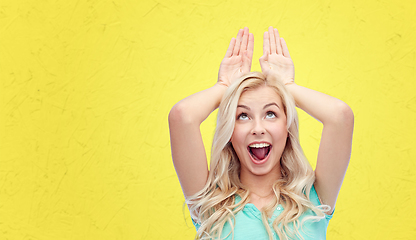 Image showing happy smiling young woman making bunny ears