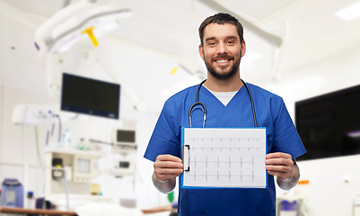 Image showing smiling male doctor with cardiogram on clipboard