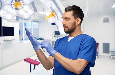 Image showing doctor or male nurse putting medical gloves on