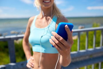 Image showing sporty young woman with smartphone and earphones