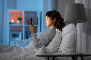 Image showing asian woman with smartphone in bed at night