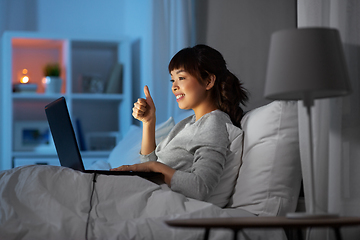 Image showing woman having video call on laptop in bed at night