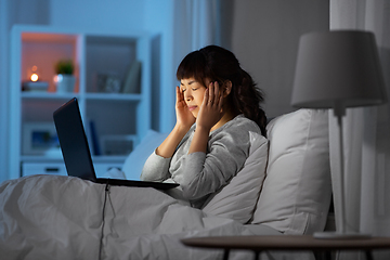 Image showing stressed woman with laptop working in bed at night