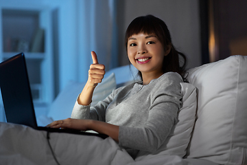 Image showing woman with laptop in bed at night shows thumbs up