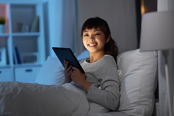 Image showing asian woman with tablet pc in bed at home at night