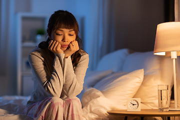 Image showing sad asian woman sitting on bed at night