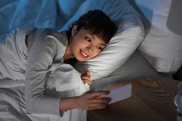 Image showing asian woman with smartphone in bed at night