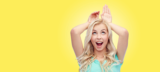 Image showing happy smiling young woman making bunny ears