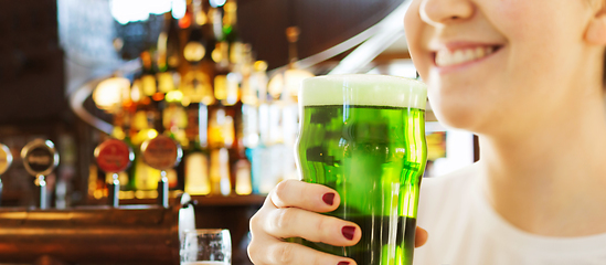 Image showing close up of woman with green beer in glass