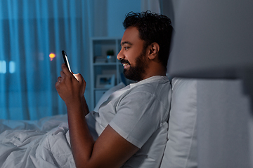 Image showing indian man with smartphone in bed at home at night
