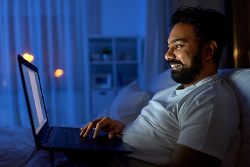 Image showing indian man with laptop in bed at home at night